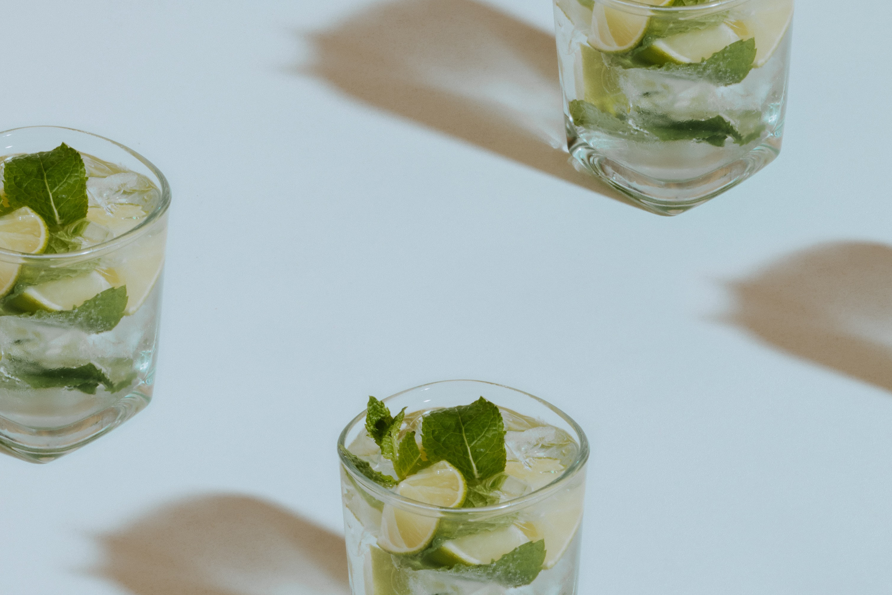 Repeated lime cocktails in diagonal pattern across image.