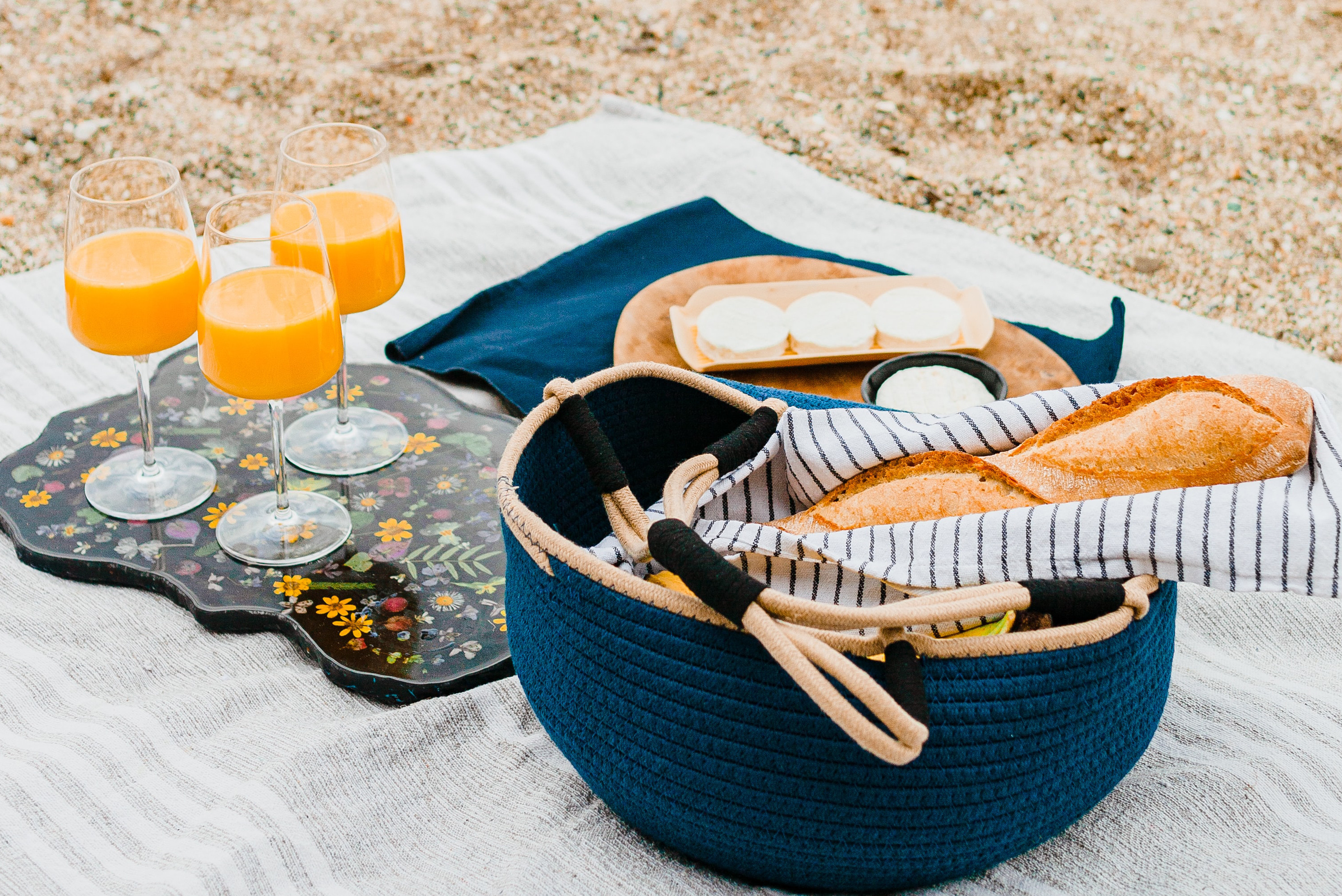 Picnic at the beach with three mimosas and food.